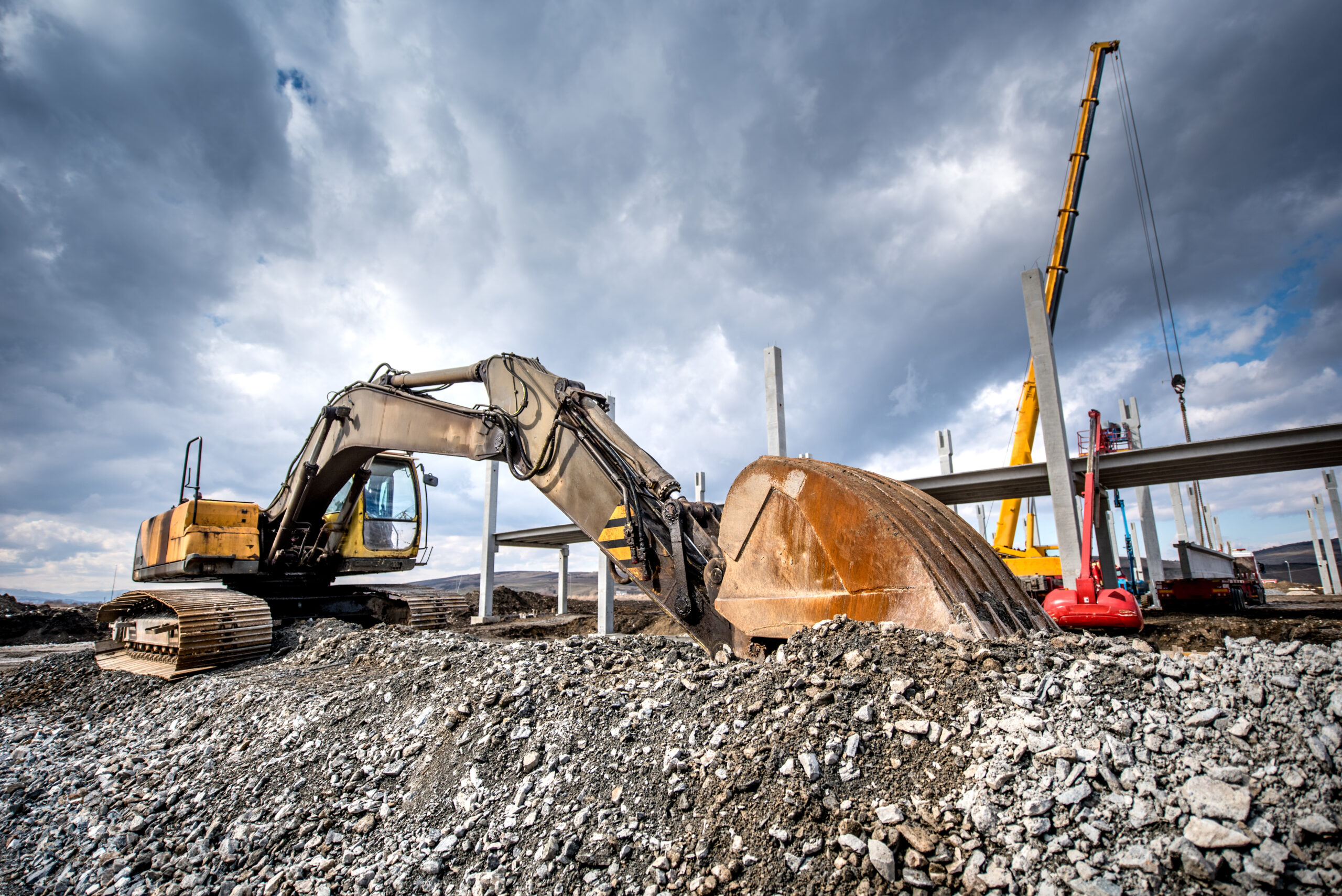 Heavy duty industrial excavator loading gravel on construction site. Details of building site Heavy duty industrial excavator loading gravel on construction site. Details of building site